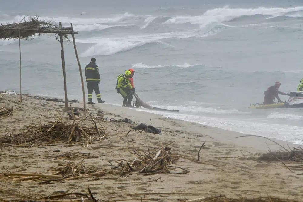 الصورة: رجال الإنقاذ ينتشلون جثة على شاطئ بالقرب من كوترو، جنوب إيطاليا، بعد أن تحطم قارب مهاجرين في البحر الهائج يوم الأحد 26 فبراير 2023. (AP Photo/Giuseppe Pipita) ©
