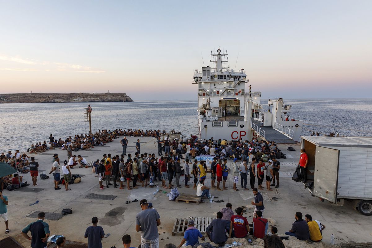 مهاجرون ينتظرون الصعود على متن سفينة تابعة لخفر السواحل الإيطالي في جزيرة لامبيدوزا، صقلية، إيطاليا، في أغسطس 2022. ديفيد لوهمويلر (أ ف ب)