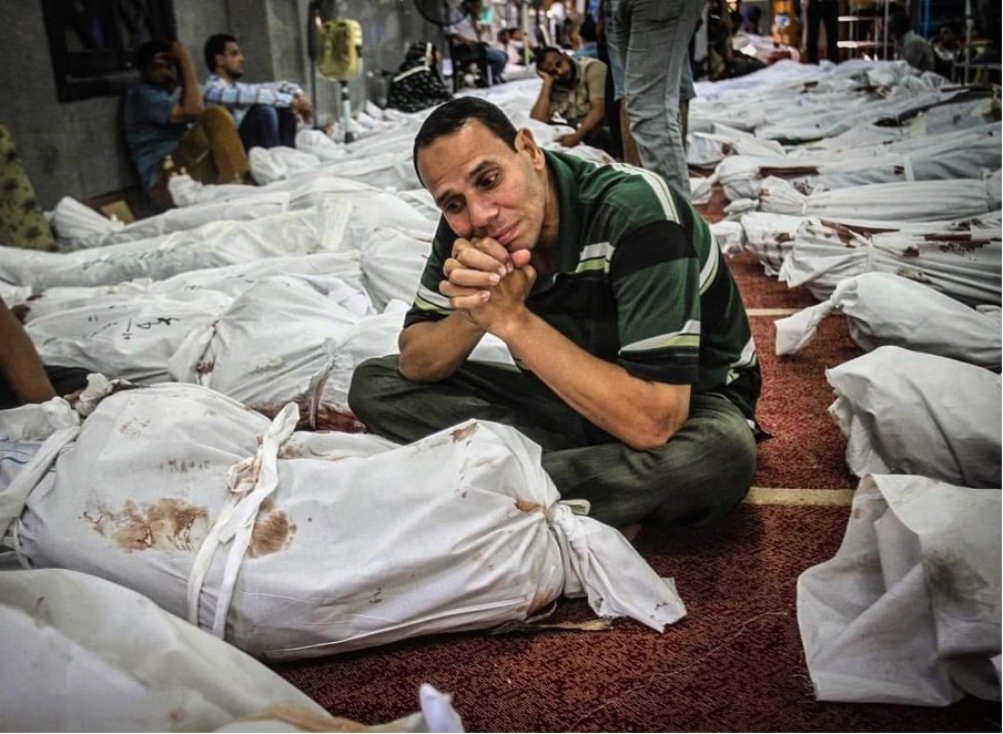 Photo: Amru Salahuddein, an Egyptian citizen sitting next to the body of his brother, who was killed during the dispersal of the Rabaa Al-Adawiya sit-in, in the Al-Iman Mosque in the Nasr City neighborhood, east of Cairo, where more than 360 bodies of other victims were. Dawn August 15, 2014